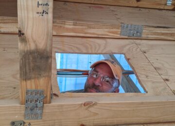 Construction worker peeking through wood